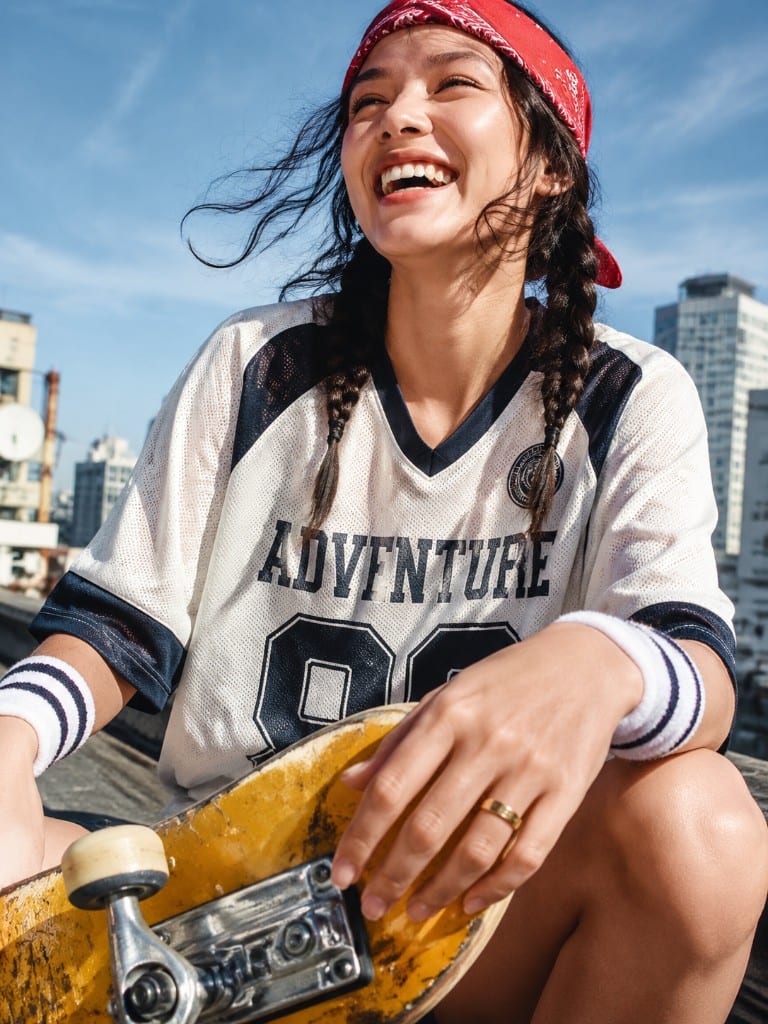 Woman laughing with a skateboard on a rooftop